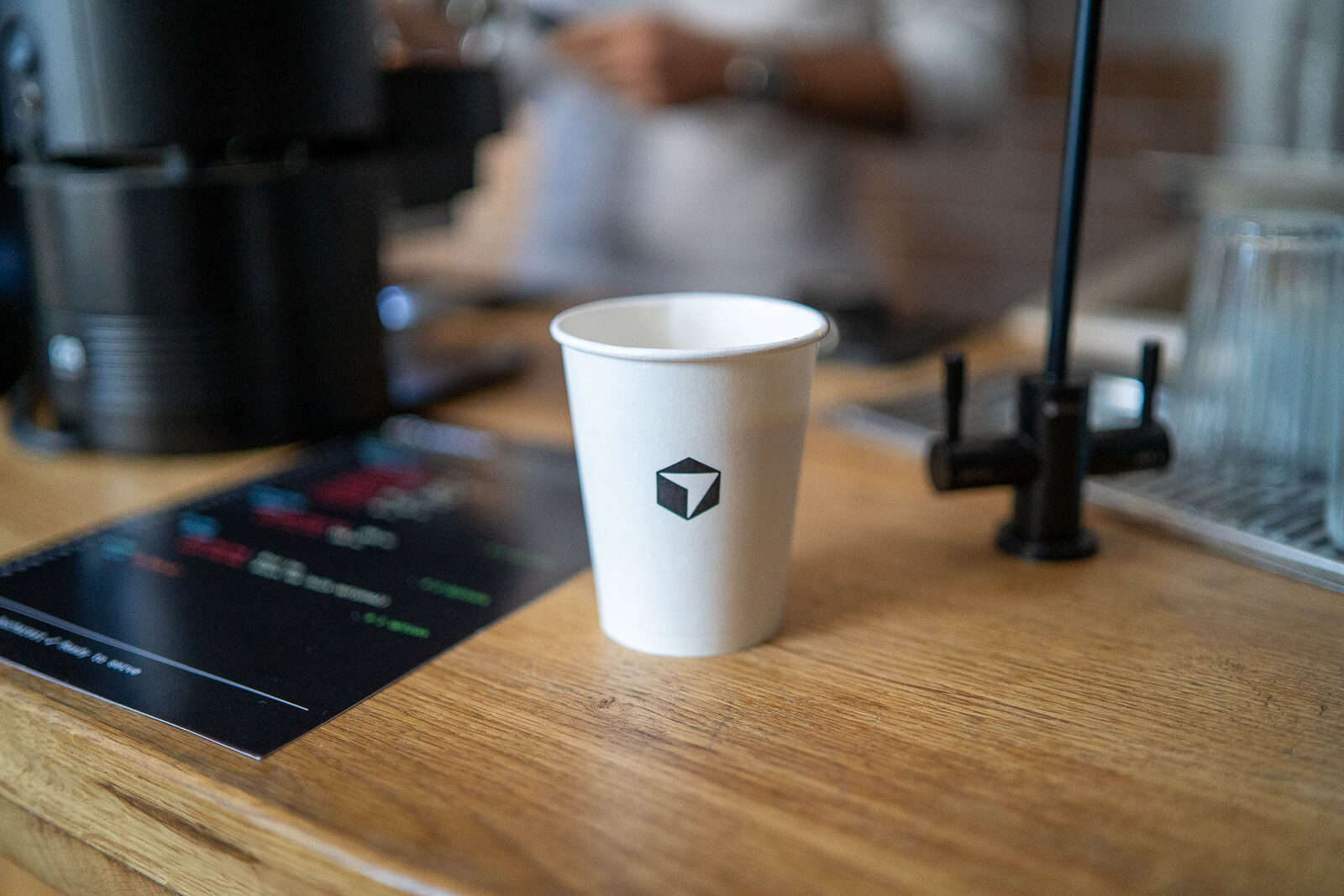 A printed coffee menu styled as a menu.yml file in Cursor’s dark editor theme, with espresso and tea options as YAML keys and a QR code commented "let’s connect".