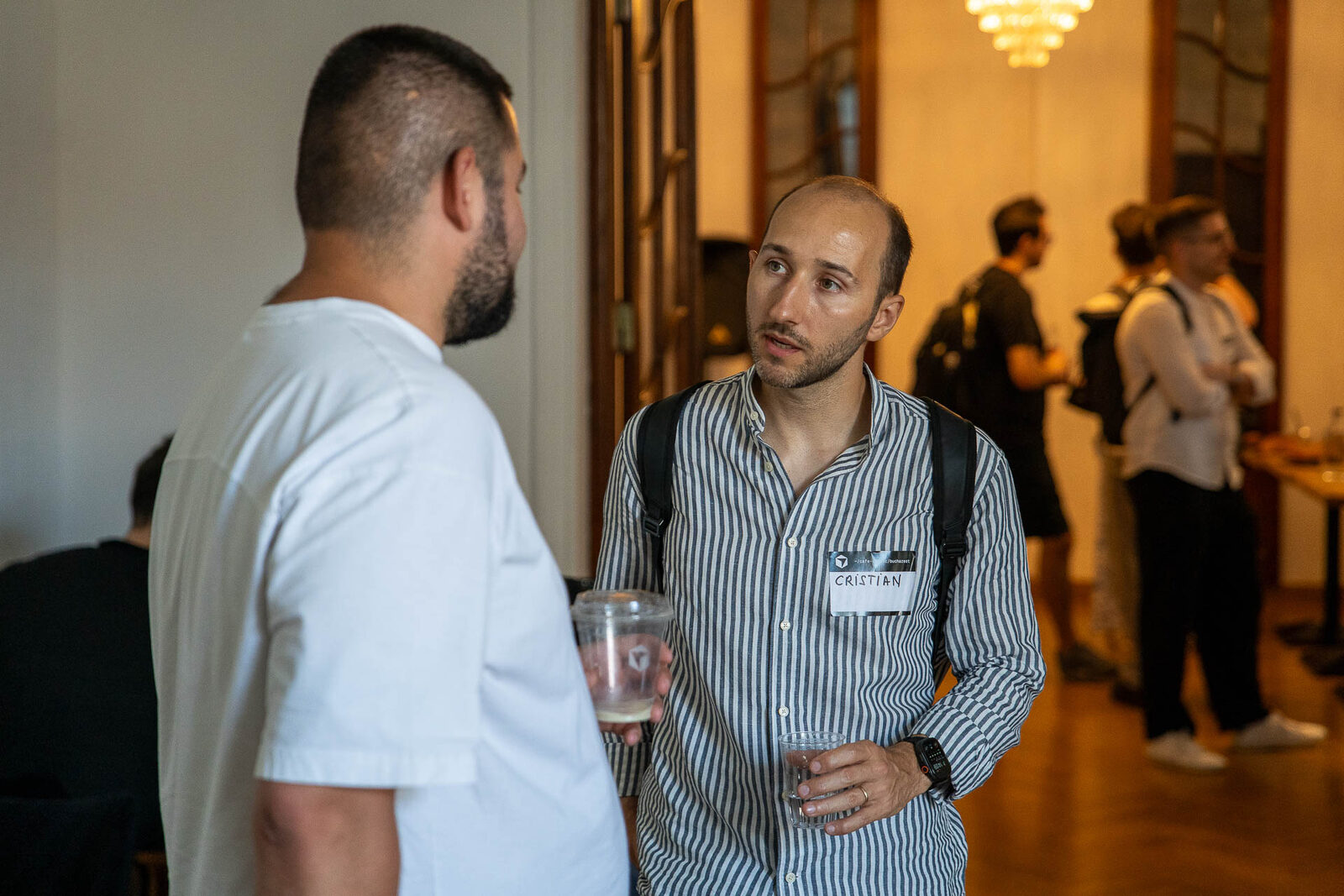 Two attendees talking over coffee at Café Cursor Bucharest, black-and-white prints of old Bucharest on the wall behind them.
