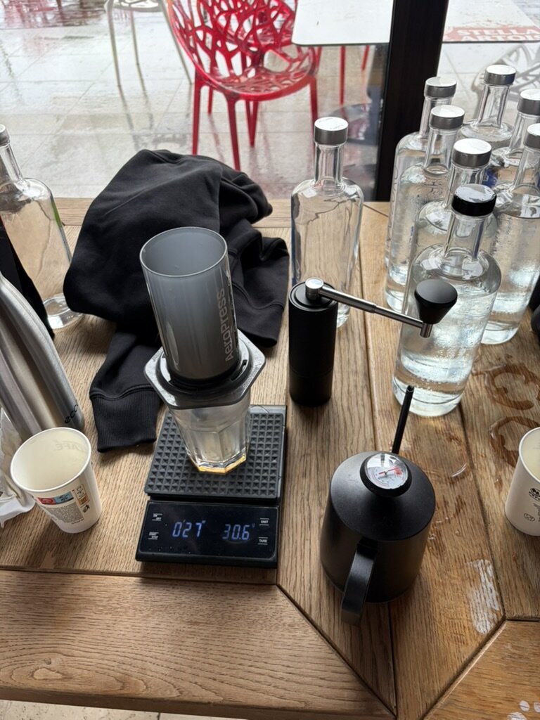 A specialty pour-over coffee setup on a wooden table at Delta Bootcamp: grinder, scale and brewer.