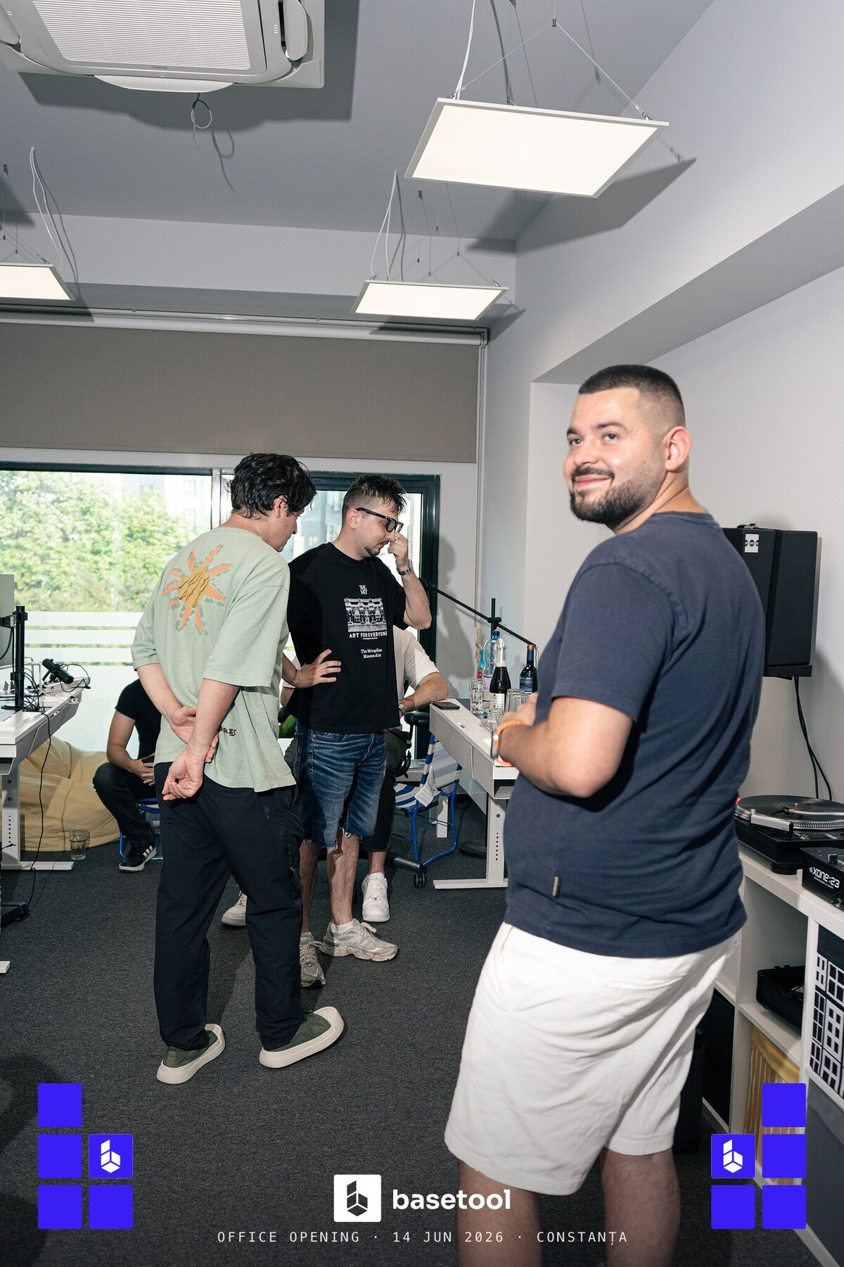 Three of the team mid-conversation in the new studio, one turning to the camera with a grin